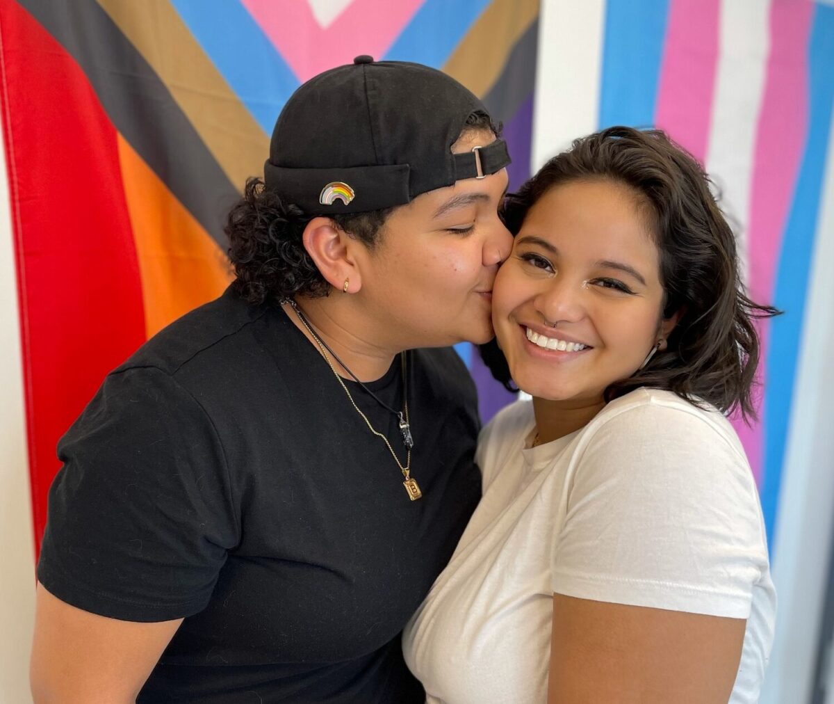 A queer couple kissing in Anchor Health's waiting room.